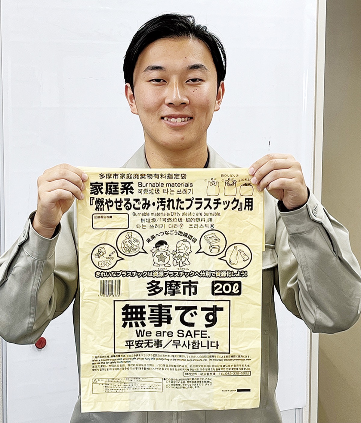 「無事です」と書かれたごみ袋を持つ市職員