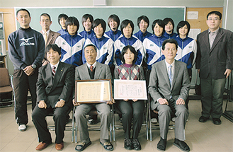 卒業生らに囲まれ、感謝状を持つ飯塚博幸監督（前列中央）