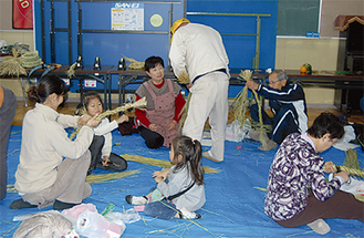 手ほどきを受けて、しめ縄を作る参加者たち＝上和田会館