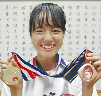 陸上女子800ｍで全国3位に入った佐藤さん右手に関東の金メダル、左手には全国の銅メダル