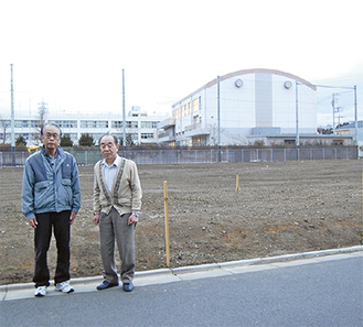 予定地の前に立つ保田会長（左）と大津さん（右）後方の建物は市立渋谷小学校