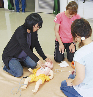 乳児の人形で心肺蘇生法を実践する参加者