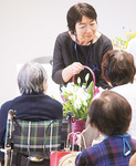 創設者の伊藤さん（左）らに花束を渡す田中理事長