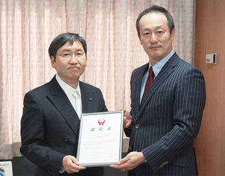 大木哲市長（左）から認定証を受け取る吉田建社長