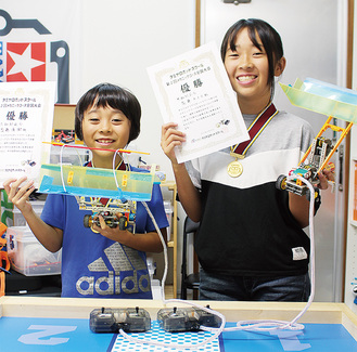 賞状とロボットを手に笑顔の斎藤あきらさん（右）と優樹君姉弟