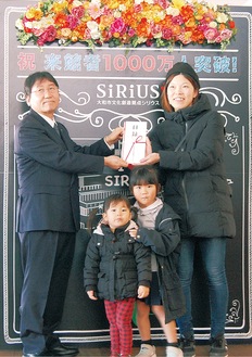 大木市長（左）から1000万人目の記念品を受け取る早稲塚永華さん、華ちゃん、桃ちゃん（右から）