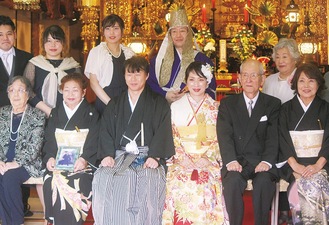 記念写真に収まる新郎・和裕さんと新婦・元子さん（前列中央）、大谷住職（後列中央）