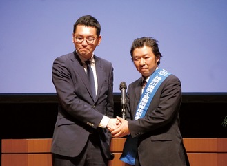 握手を交わす柴田前会長（写真左）と日高新会長