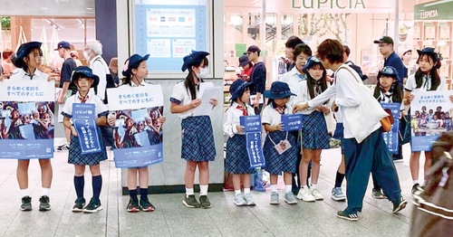 駅前で呼びかける団員たち＝提供