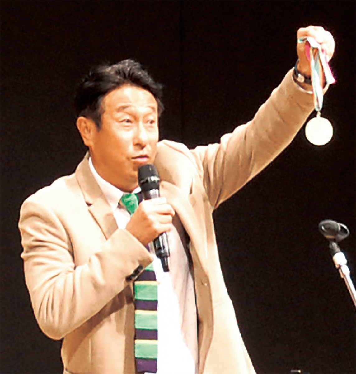 現役時代に獲得したロス五輪金メダルを掲げる宮本さん