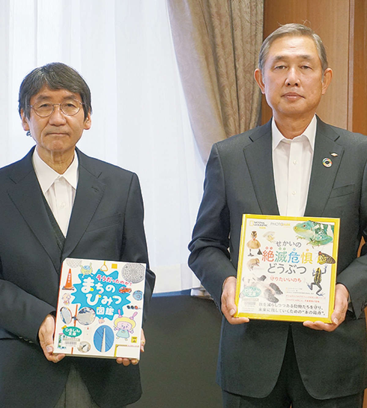本を手にする大木哲市長(左)と曽我専務理事