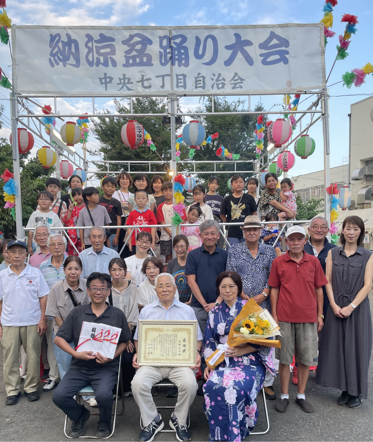 感謝状を持つ政森さん(中央)と寄贈されたやぐら(後方)