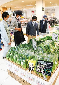 売り場に並ぶ旬の野菜と関係者＝4月30日撮影