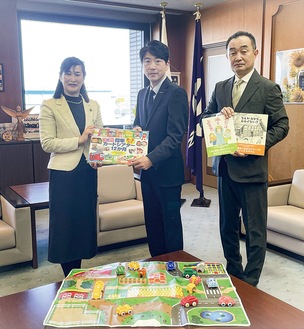 佐藤市長に絵本を手渡す北村課長（中央）と福地さん（右）