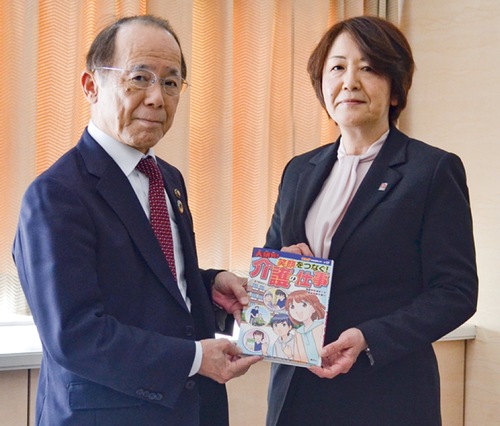学習まんがを贈呈する雨宮本部長（右）