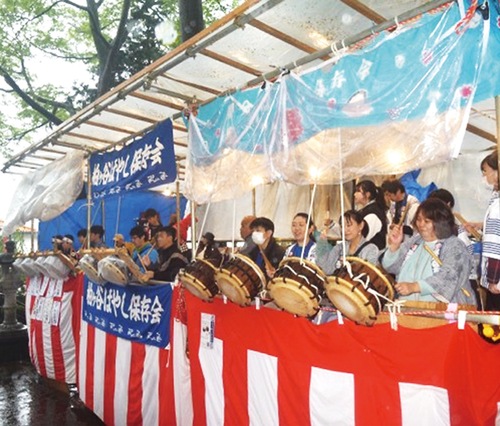 10基の太鼓が並んだ屋台　雨の中懸命に叩く