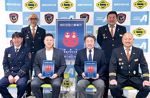 表示証を手に持つオーククリーンの柏木社長（中央左）と湘央学園の荻野学科長（中央右）提供・同市消防本部