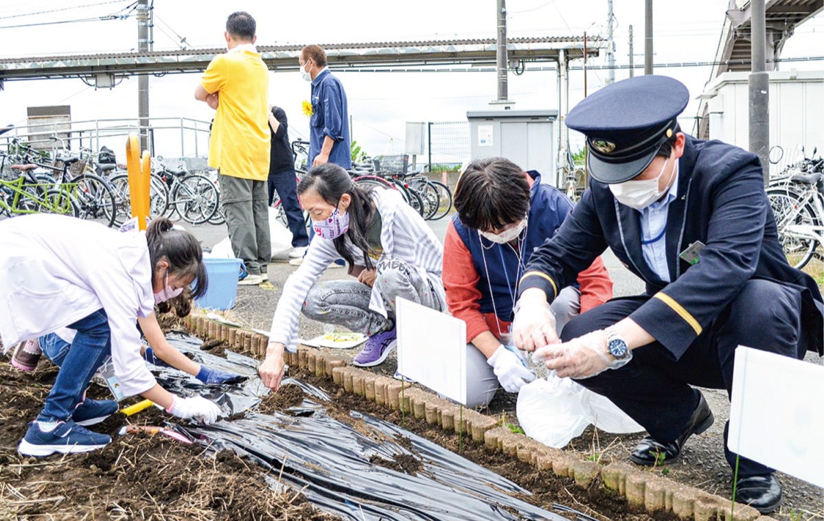 入谷駅前で種を植える参加者