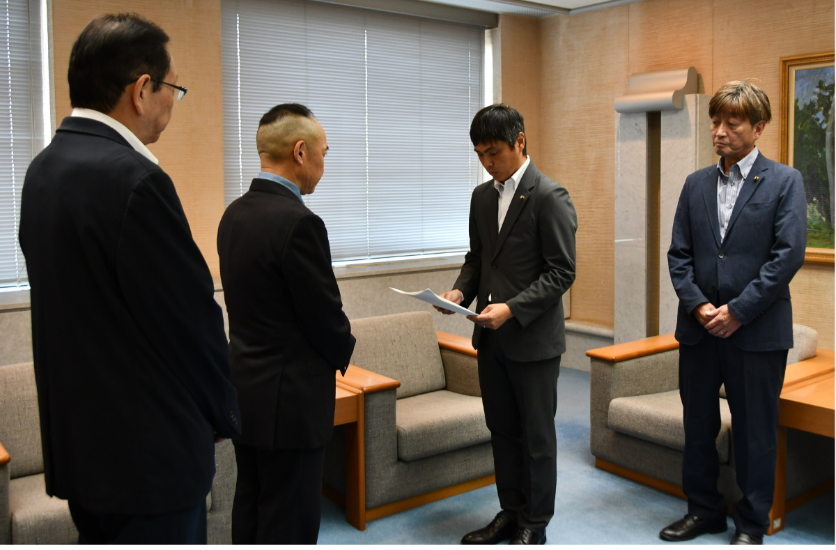 松橋議長に答申書を読み上げる竹田委員長、右・京免康彦副委員長 、左・加藤学副議長=8月24日・座間市議会内
