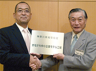 座間市商工会の大塚和光会長（右）と握手する比留川社長