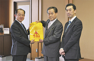 飯島会長（中央）がカバーを遠藤市長に手渡した