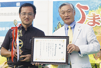 大塚和光商工会長（右）から賞状とトロフィーを受け取った櫻田オーナー
