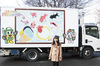 作品が描かれたトラックを前に、笑顔をみせた阿部さん