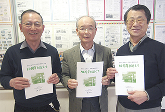 10周年記念誌を手にする濱本委員長（中央）、実行委員長の甲斐晴男さん（左）、記念誌を手掛けた鈴木英夫さん