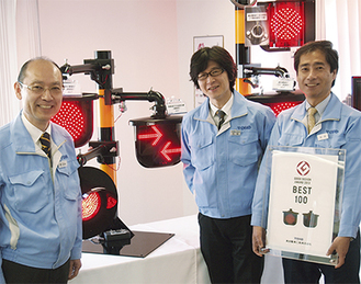 踏み切り警報灯などを製造している。左から指定を喜ぶ渡辺晃充さん、村田さん、岩田清さん
