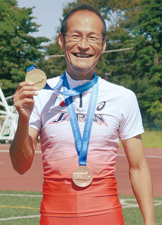 金メダル、銅メダルを手に笑顔の宮本義久さん