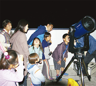 天体望遠鏡でパンスターズ彗星を観察する児童