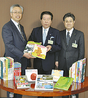 本を渡す鶴井常務理事（左）