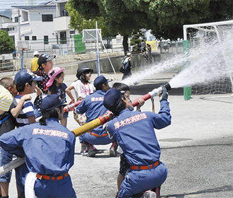 消防団員の指導を受けながら放水体験をする子どもたち