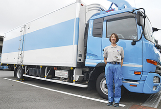 4トン車の前に立つ松本恭子さん（46）。ご当地グルメのお気に入りは、刈谷パーキングエリア（愛知県）の海老せんべい。車中では息抜きにチョコレートを口にしたり、大好きな矢沢永吉さんの「安物の時計」を聴いている