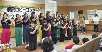 「歌って、踊って、演奏して」。湘北短期大学の学生らが登場した15回目のコンサートのようす。約１時間のステージの締めくくりは出演したサークルメンバーが総出演。ロビーに集まった入院患者らと地域から訪れた観客が一体になって楽しんだ