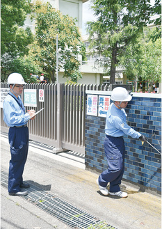 塀の安全性を確認する市職員