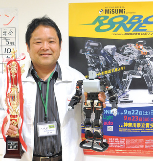 大会に出場したロボットとトロフィを手にする萩原さん。「Ｄｒ（ドクター）．ＧＩＹ（ギー）」のハンドルネームで大会に出場している
