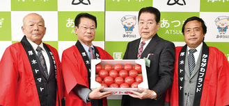 トマトを手渡す部会員（左から和田さん、木原さん、小林市長、神崎さん）