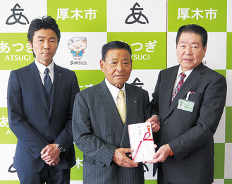小林常良厚木市長（右）に寄付金を手渡す、株式会社アオイの篠田勝已会長（中央）。