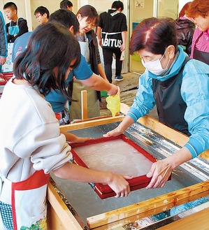 「すげた」を使って和紙の材料を均一に広げていく児童