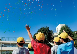 １２５周年記念で飛ばした風船を見守る児童たち