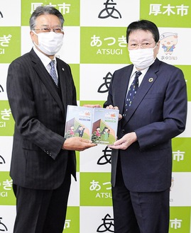 ＤＶＤを手渡す平井理事長（左）と受け取る小林市長