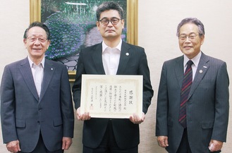 小野澤町長（左）から感謝状を受け取った佐々木社長（中央）と萱英二代表取締役会長（右）
