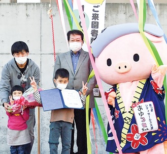 １千万人目の来園者となった中村さん親子と祝福する小林市長（中央右）、あゆコロちゃん