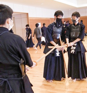 中学生（右）に木刀の握り方を教える高校生