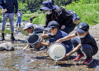 鮎を川に放流する児童
