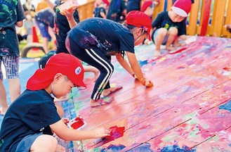 園舎に色を塗る児童