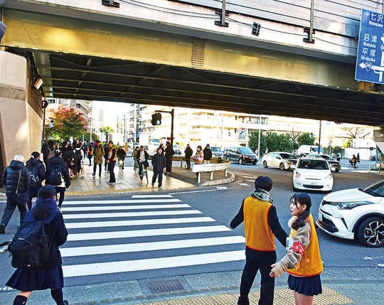 オレンジ色のビブスを着て歩行者を誘導する生徒