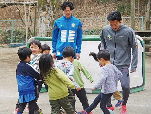 保育園児と一緒にプレーする選手２人