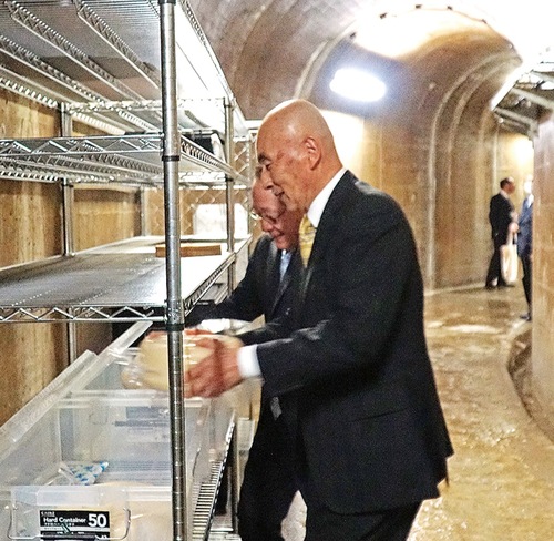 チーズを棚に置く服部代表（手前）と小野澤町長（奥）